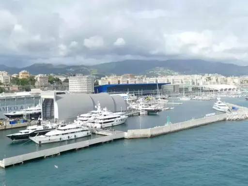 Porto con yacht di lusso ormeggiati, sullo sfondo la città e le montagne. Un'immagine che fa sognare, ma il costo medio crociera è da valutare.