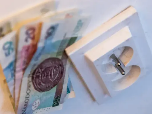 Pieniądze leżą obok gniazdka elektrycznego. Czy to symbolizuje pge brak faktury i rachunków do zapłaty?