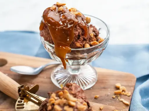 En skål med chokladglass, toppad med kolasås och nötter. Perfekt för ett chokladglass recept!