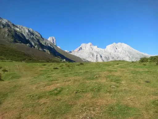 Majestatyczne szczyty Picos de Europa, w tym charakterystyczny Torre de Cerredo, wznoszą się nad zieloną doliną.