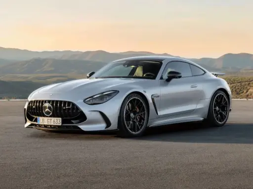 Un elegante Mercedes GTR plateado descansa en una carretera desierta, con montañas onduladas al atardecer de fondo.