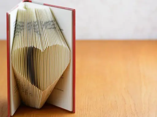 Ein Buch, dessen Seiten zu einem Herz gefaltet sind. Eine kreative Idee für ein Geldgeschenk, Buch basteln.