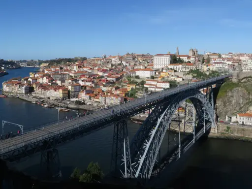 El icónico puente de Oporto cruza el río Duero, conectando la ciudad con sus coloridas casas y barcos turísticos.
