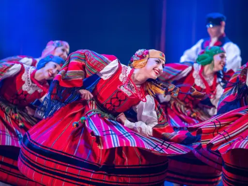 Tancerki Zespołu Mazowsze w barwnych strojach ludowych wirują w radosnym tańcu.