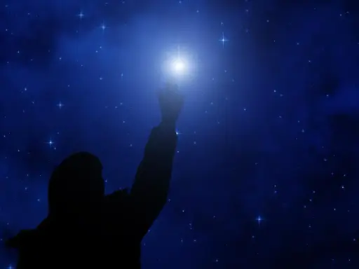 Sylwetka człowieka sięga ku jasnej gwieździe polarnej na tle nocnego, gwiaździstego nieba.
