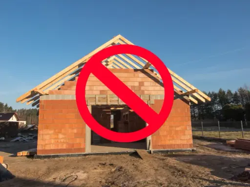 Budowa domu w toku, ale czerwony znak zakazu sugeruje problemy z legalizacją samowoli budowlanej.