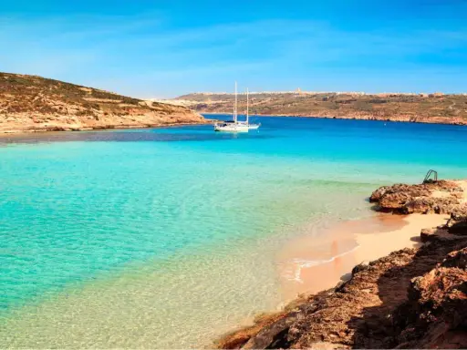 Traumhafter Malta Strand mit türkisfarbenem Wasser, einer einsamen Bucht und einem Segelboot. Perfekt für einen entspannten Urlaub.