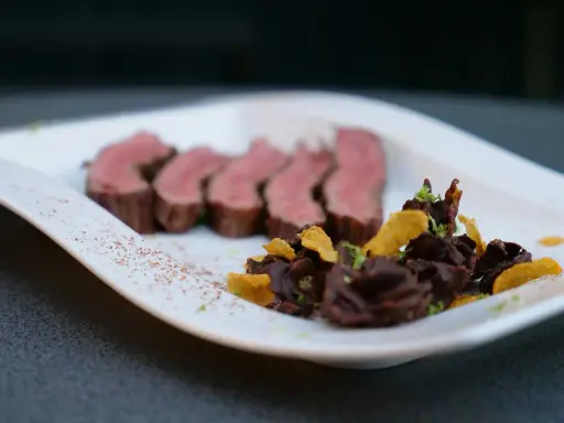 Saftiges Flank Steak, in Scheiben geschnitten, serviert mit dunkler Schokolade und knusprigen Chips.