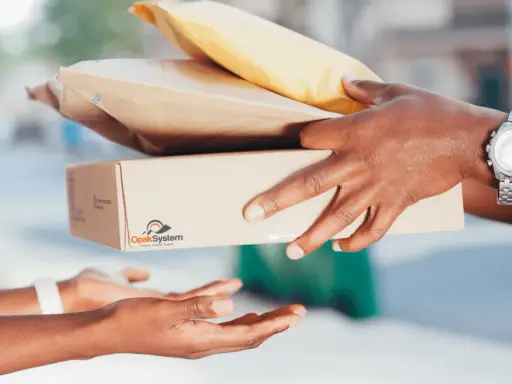 Ręce przekazują sobie paczki i koperty – idealne, by w co zapakować paczkę na Vinted.