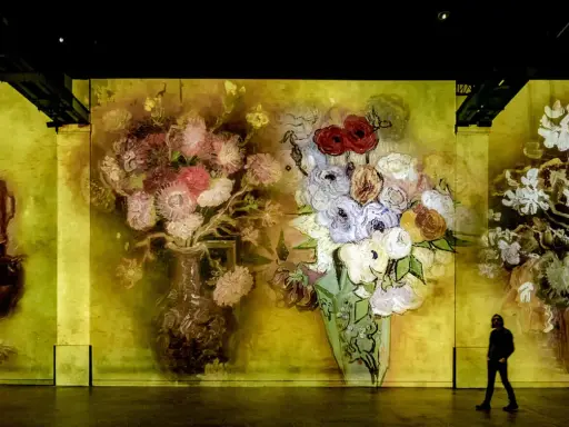 En person går förbi en väggprojektion av Van Goghs blomsterbuketter, en hyllning till hans tid i Paris.