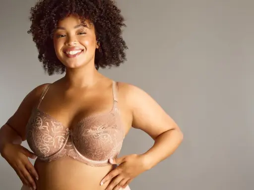 Donna sorridente con tette grandi perfette in reggiseno di pizzo color carne.