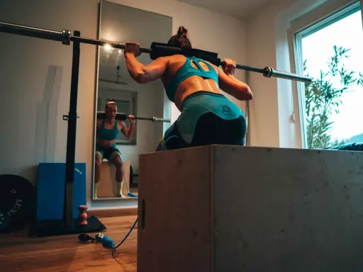Frau beim Krafttraining für Triathlon, macht Kniebeugen mit Langhantel.