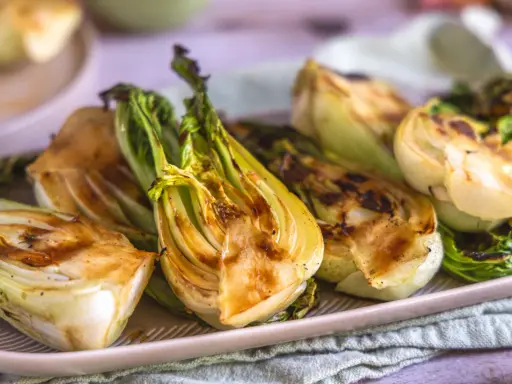 Halbierte Pak Choi-Stücke, die auf einem Teller mit Grillspuren liegen. Köstlich und gesund!