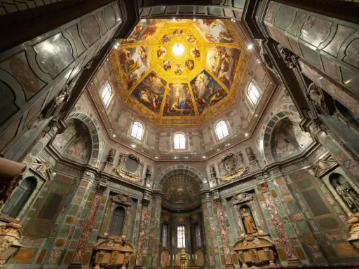 Intérieur de la Chapelle des Médicis, dôme orné de fresques dorées et de peintures religieuses, murs décorés de marbre et de sculptures.