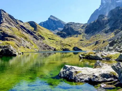 Lago alpino dalle acque smeraldine, incastonato tra montagne scoscese e verdi pendii. Un angolo di pace nell'Italia del Nord.