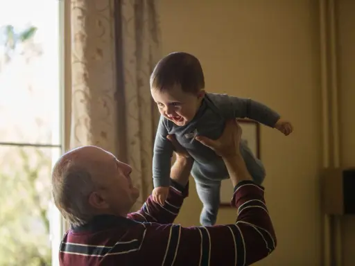 Dziadek podrzuca radosnego wnuka. Czy dziadkowie muszą płacić alimenty za syna? To pytanie, które nie ma związku z tą ciepłą chwilą.