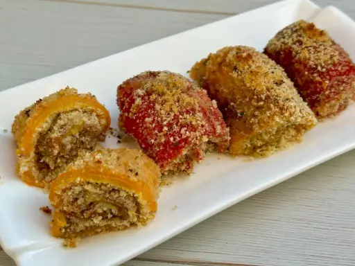 Involtini di peperoni ripieni e gratinati, serviti su un piatto bianco.