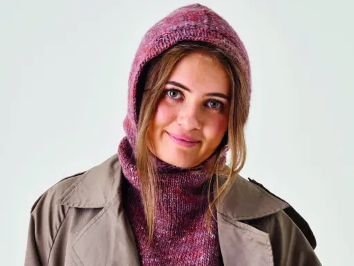 Ung kvinna med stickad balaclava i rosa toner och en beige kappa. Perfekt för barn som vill sticka en egen balaclava.