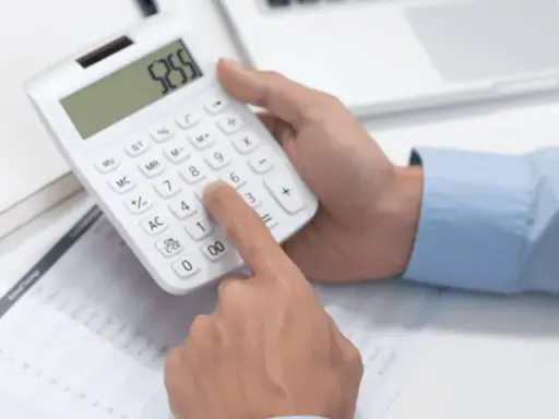 Ręce liczą na kalkulatorze, analizując dane finansowe. To pokazuje, co to jest moc przyłączeniowa w kontekście zarządzania zasobami.