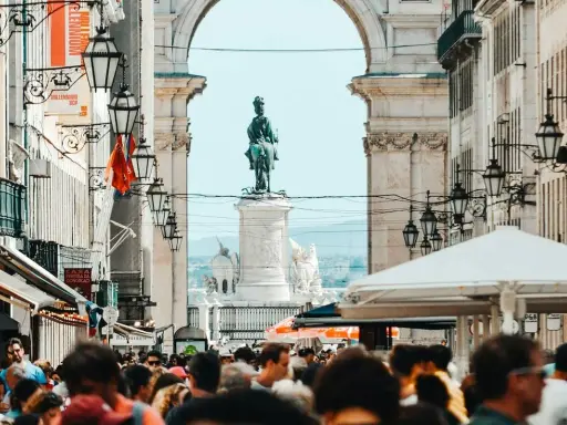 Menschenmenge auf der Rua Augusta in Lissabon mit Reiterstatue und Triumphbogen im Hintergrund.
