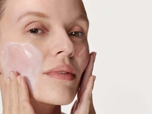 Donna applica delicatamente crema viso con le dita, un gesto semplice per prendersi cura della pelle.