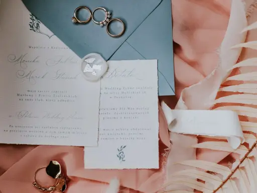 Eleganckie wypisywanie zaproszeń ślubnych z obrączkami i pieczęcią lakową.
