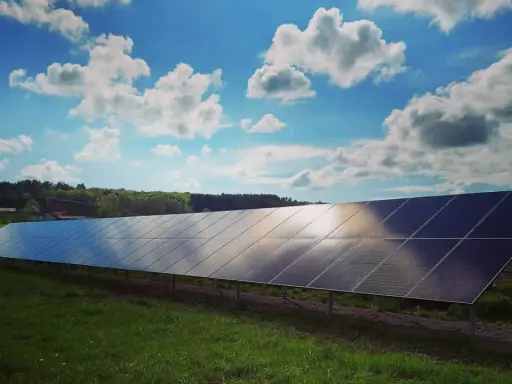 Lång rad solpaneler fångar solljuset under en molnig himmel. Solkraft EMK AB bidrar till en grönare framtid.