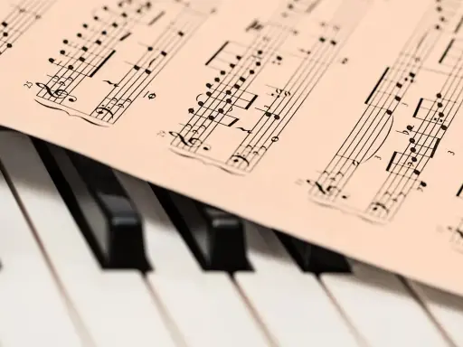 Partytura muzyczna na klawiaturze pianina. Widoczne nuty i klucze, które oddają bogate **cechy muzyki barokowej**.
