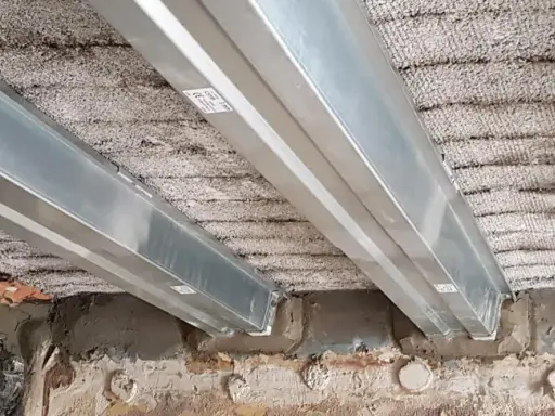 Vigas metálicas instaladas para como reforzar una viga de madera dañada por el fuego. Se observa el soporte de las nuevas vigas sobre la estructura existente.