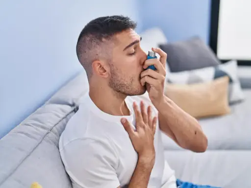 Mężczyzna używa inhalatora, szukając ulgi w objawach astmy. Leki na astmę bez recepty mogą pomóc w łagodzeniu napadów.