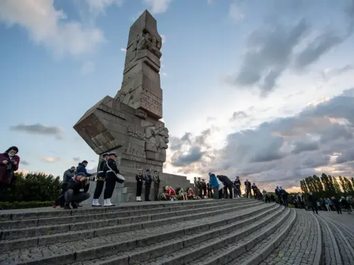 Uroczystość przy Pomniku Obrońców Wybrzeża na Westerplatte w Gdańsku. Warty honorowe, wieńce i zgromadzeni ludzie.