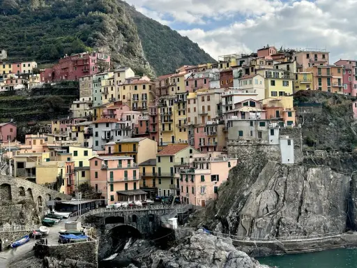 Case colorate aggrappate alla roccia, un paesaggio da cartolina. Cinque blues per la banda Monterossi, un'armonia di tinte vivaci che abbraccia il mare.