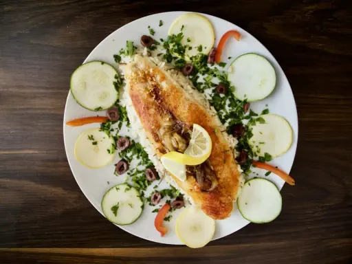 Ryba z ryżem, cytryną, oliwkami i warzywami. Pyszne danie w stylu dieta śródziemnomorska.