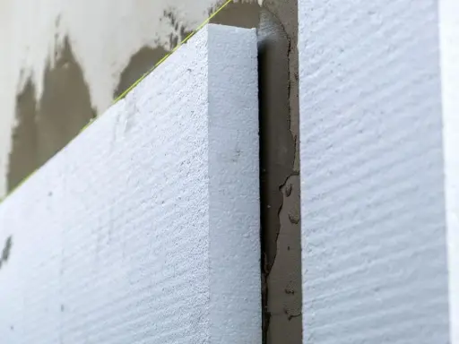 Aislamiento de poliestireno expandido en una pared, paso clave para **edificios eficientes** y confortables.