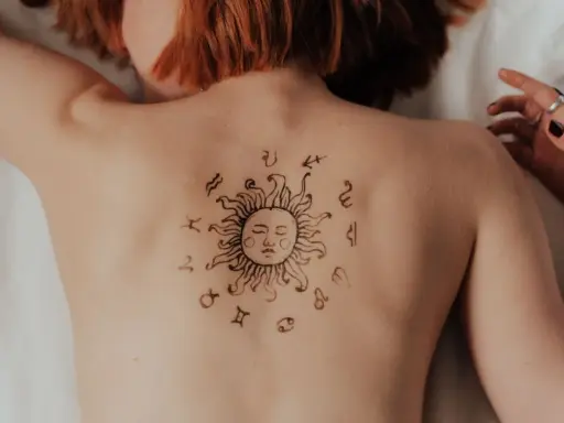 Tatuaż na plecach: słońce otoczone znakami zodiaku. Może symbolizuje ascendent w Lwie, emanujący energią i pewnością siebie.