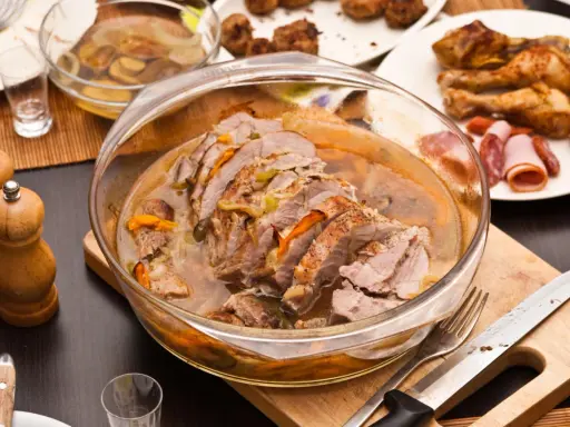Pyszny schab w sosie, podany w szklanej misie, z dodatkami na talerzach.