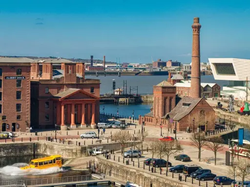 Albert Dock in der Liverpool Stadt, mit einem gelben Amphibienfahrzeug im Wasser und einem hohen Schornstein.