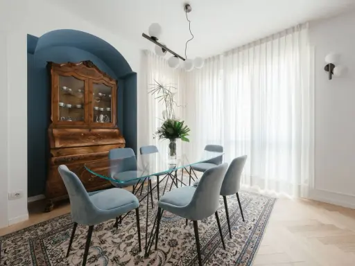 Un soggiorno classico con un mobile antico e un tavolo in vetro. I colori delle pareti, un blu intenso, creano un'atmosfera elegante.