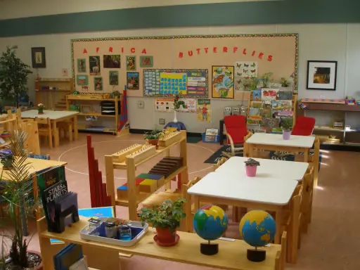 Klasa przygotowana zgodnie z metodą Montessori: globusy, książki o Afryce i motylach, materiały edukacyjne na półkach.