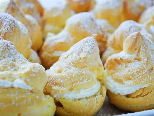 Une assiette de choux à la crème, saupoudrés de sucre glace. Ces petites merveilles de chou patisserie sont prêtes à être dégustées.