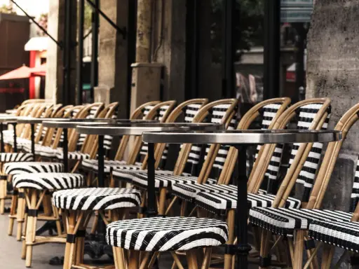 Terrasses parisiennes avec chaises et tabourets rayés, prêts à accueillir les gourmands pour déguster les spécialités paris.
