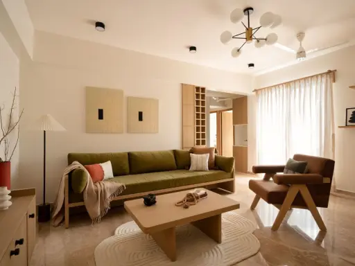 Soggiorno in stile Japandi con divano verde, poltrona in pelle, tavolino in legno e opere d'arte minimaliste.