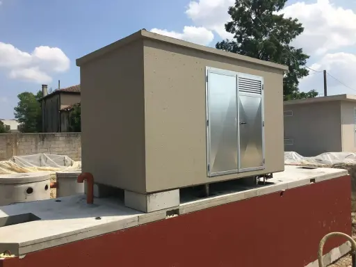 Edificio prefabbricato con porte metalliche, probabilmente per ospitare una pompa soprabattente, su una base in cemento.
