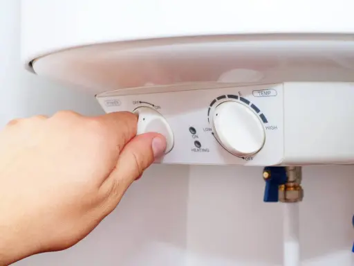 Mano ajustando el dial de potencia de un termo eléctrico. Si el termo pita, puede ser por un ajuste incorrecto de temperatura o por un problema de calentamiento.