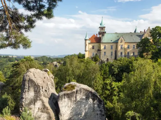 Zamek Hrubá Skála, wspaniały przykład tego, co warto zobaczyć w Czechach, wznosi się nad skalistym krajobrazem i bujną zielenią.