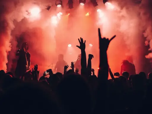 Tłumy na jednym z corocznych festiwali w Polsce, wznoszą ręce w górę, otoczone dymem i czerwonym światłem sceny.