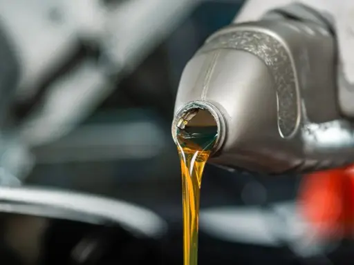 Huile moteur dorée versée d'une bouteille, illustrant la viscosité.