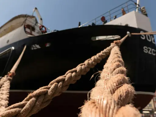 Gros cordage tressé, essentiel au point d'amarrage d'un navire noir et blanc sous un ciel bleu.