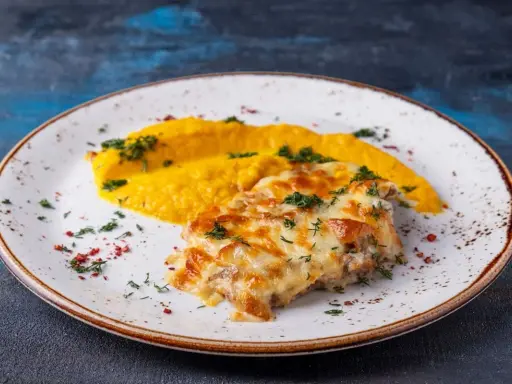 Schab po zbójnicku z purée z dyni, posypany zieloną pietruszką i czerwonym pieprzem.