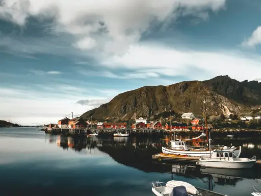 Malowniczy norweski port z czerwonymi domkami i łodziami. Czy do Norwegii trzeba mieć paszport? Sprawdź przed podróżą!